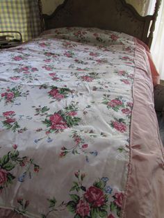 a bed with pink and green floral bedspread next to a window in a bedroom