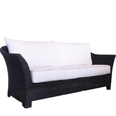 a black wicker couch with white pillows on it's back and side ends