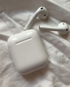 an apple airpods sitting on top of a white bed next to another pair of headphones