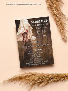 a wedding card with the bride's dress and boots on it next to some dried grass