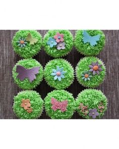 cupcakes decorated with green frosting and colorful flowers are arranged in the shape of hearts