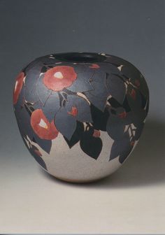 a black and white vase with red flowers on it