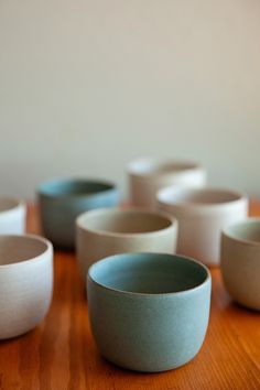 several white and blue bowls sitting on top of a wooden table