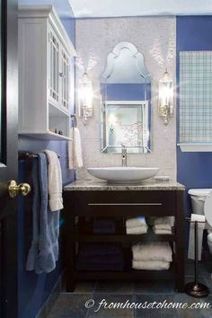 a white toilet sitting next to a sink in a bathroom under a mirror and lights