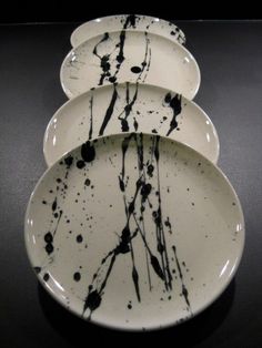 three white plates with black splatters on them