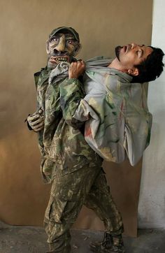 a man in camouflage carrying another man on his back