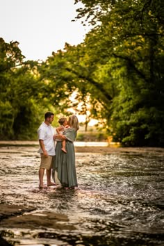 a man and woman standing in the middle of a river with their arms around each other