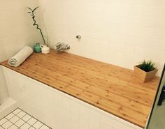 a bamboo counter top in a bathroom next to a plant and toilet paper on the wall