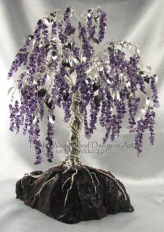 a wire tree sculpture with purple flowers on it