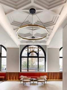 an empty room with two couches and large windows on the wall behind them, in front of a wooden paneled ceiling