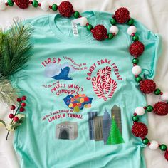 a t - shirt with the words merry christmas on it, surrounded by pom poms