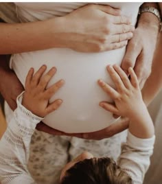 two adults and one child are holding the belly of a pregnant woman with their hands on her stomach