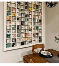 a dining room table with plates and cups on the wall next to a potted plant