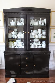 a black china cabinet filled with white dishes