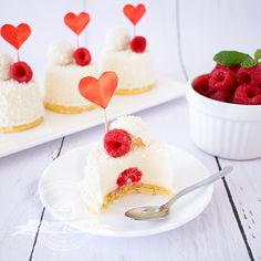 two small cakes with hearts on top and raspberries in the background