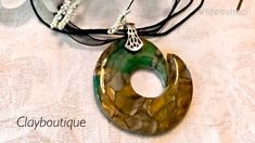 a necklace with a green and brown pendant on it's side, sitting on top of a table