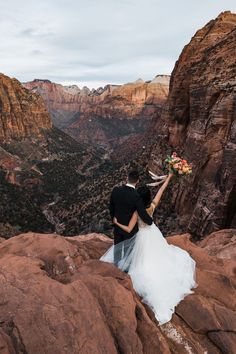 a bride and groom standing on top of a mountain