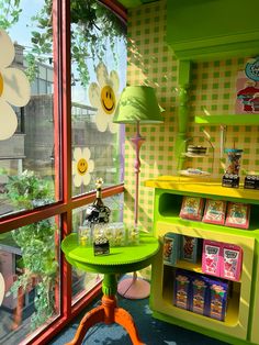 a green table sitting in front of a window next to a shelf filled with books