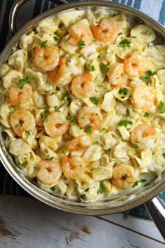 a bowl filled with pasta and shrimp on top of a table