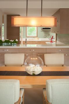 a dining room table with chairs and a bowl filled with flowers on top of it