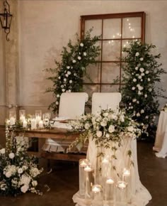 a table topped with lots of white flowers and candles