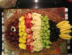 a platter with grapes, bananas, pineapples and other fruit arranged in the shape of a fish