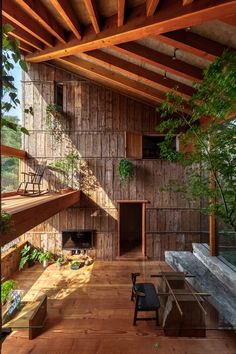 an outdoor living area with wooden walls and flooring, surrounded by greenery on both sides