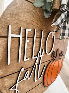 a wooden sign that says hello fall and has a pumpkin on the front with a bow