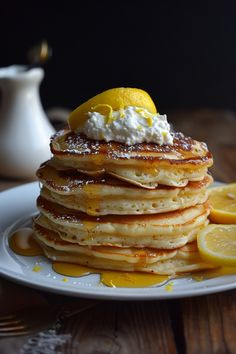 Stack of pancakes topped with whipped cream, lemon slices, and syrup on a white plate. Ricotta Lemon Pancakes, Lemon Ricotta Pancakes With Bisquick, Gluten Free Lemon Ricotta Pancakes, Gourmet Pancakes, Lemon Ricotta Pancakes With Blueberry Syrup, Lemon Pancakes