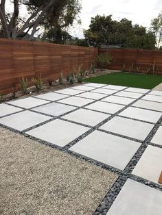 an outdoor area with grass, gravel and wood fenced in areas that have been designed to look like stone tiles