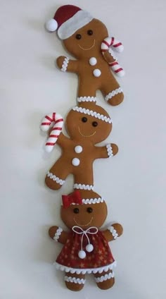 three gingerbread man and woman ornaments are hanging on the wall, decorated with candy canes