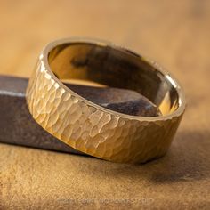 a gold wedding ring sitting on top of a wooden table