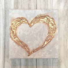 a heart made out of gold chains sitting on top of a white wooden table next to a wall