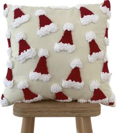 a pillow with santa hats on it sitting on a wooden chair in front of a white background