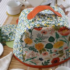 a flowered bag sitting on top of a table next to plates and silverware