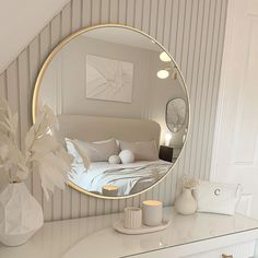 a bedroom with a large round mirror on the wall next to a dresser and bed