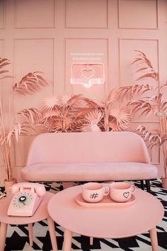 a pink couch and coffee table in a living room with palm leaves on the wall