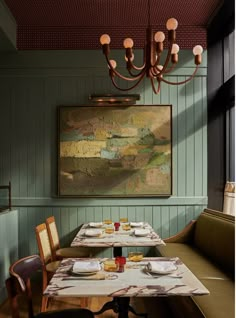 a dining room with green walls and wooden table set up for two people to eat