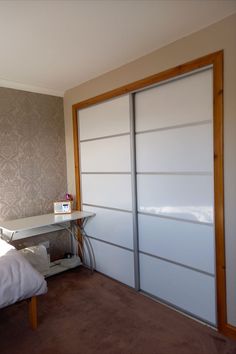 a bedroom with a bed, desk and sliding glass closet doors in the middle of it