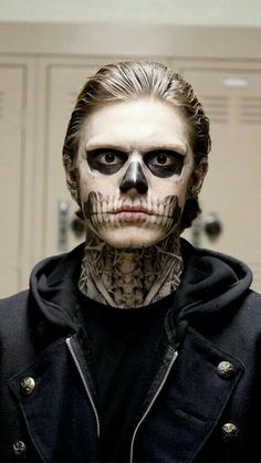 a man with skull makeup and piercings on his face is looking at the camera