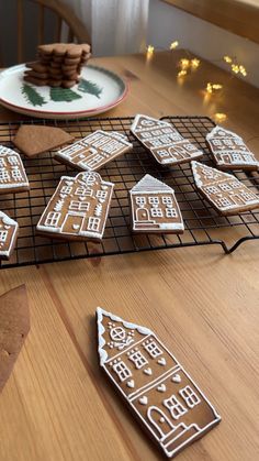 gingerbread cutouts sitting on a cooling rack next to plates with cookies in the shape of houses