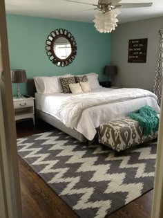 a bedroom with a bed, rug and mirror