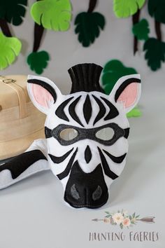 a zebra mask sitting on top of a white table next to a suitcase and trees