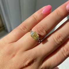 a woman's hand with a yellow and white diamond ring on her left hand