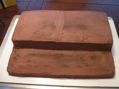 two square brownies sitting on top of a white plate covered in chocolate frosting