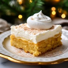 a piece of cake with whipped cream on top sits on a plate next to a christmas tree