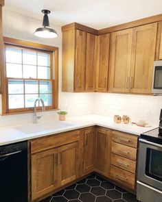 a kitchen with wooden cabinets and white counter tops, black tile flooring and stainless steel appliances