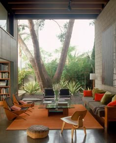 a living room filled with furniture and lots of trees in the back drop down area