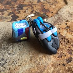 two pairs of shoes shaped key chains sitting on top of a stone surface with rocks in the background