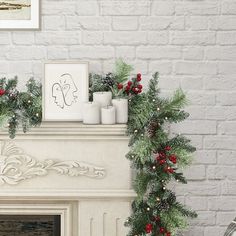 a fireplace decorated with christmas greenery and candles